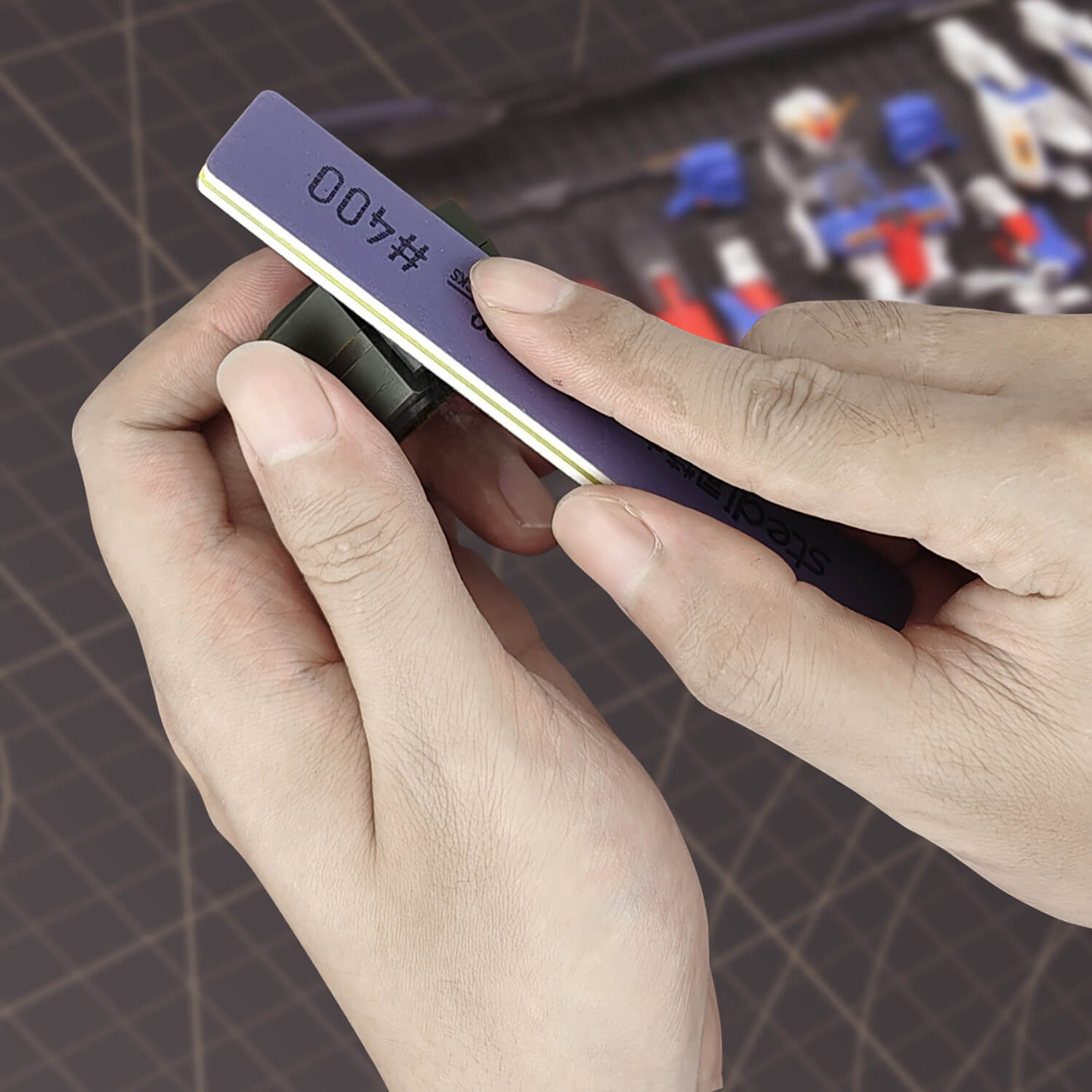Close up of a modeler using stedi #400 grit sanding stick on a plastic part.